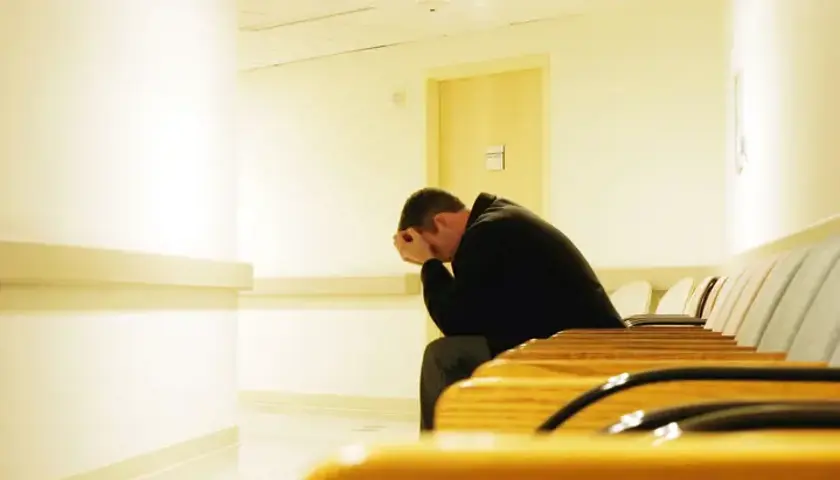 Patient With Head In Hands In Waiting Room